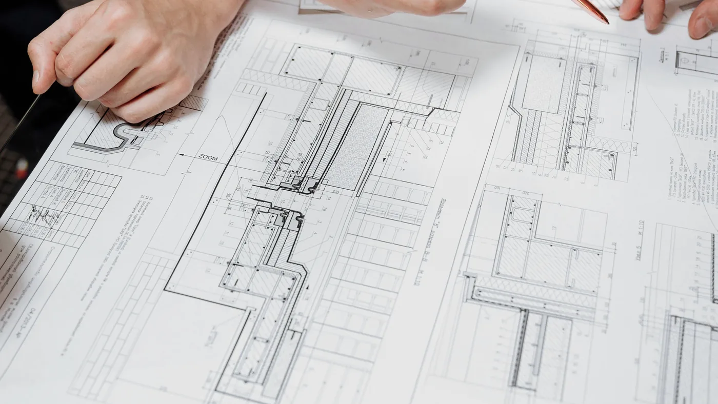Hands spreading out a detailed architectural plan